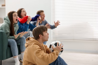 Photo of Emotional football fans watching game together indoors, selective focus. Space for text