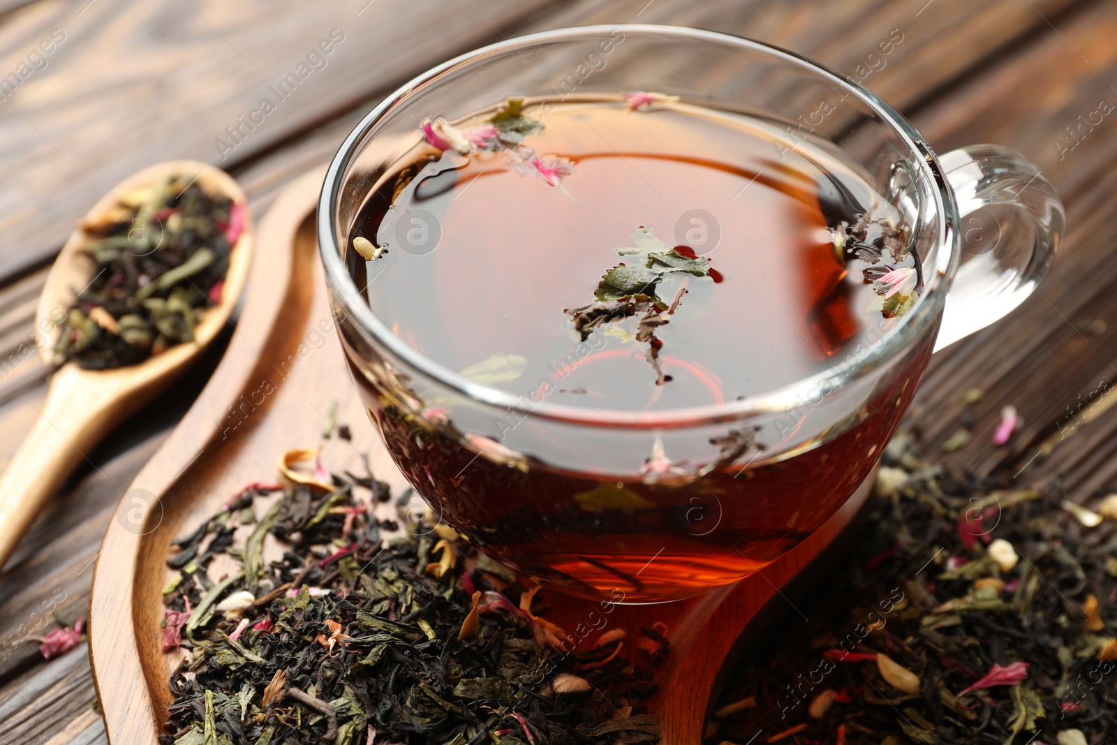 Aromatic herbal tea in glass cup and dry leaves on wooden table, closeup Photo of Aromatic herbal tea in glass cup and dry leaves on wooden table, closeup