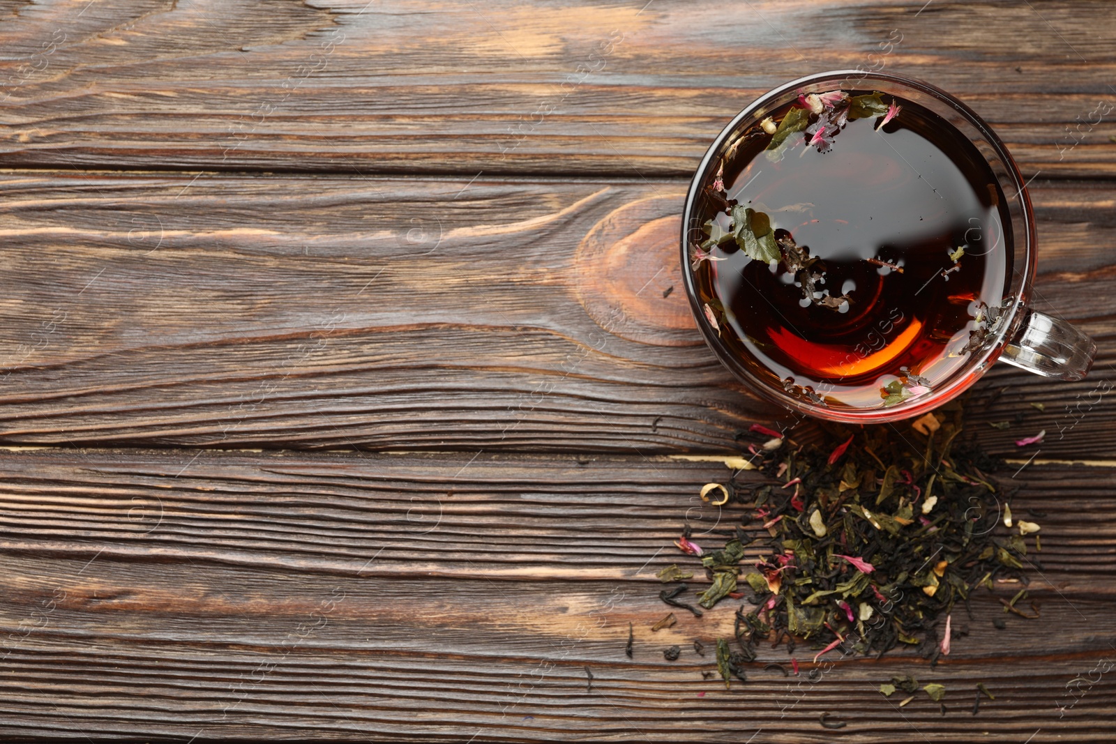 Aromatic herbal tea in glass cup and dry leaves on wooden table, flat lay. Space for text Photo of Aromatic herbal tea in glass cup and dry leaves on wooden table, flat lay. Space for text