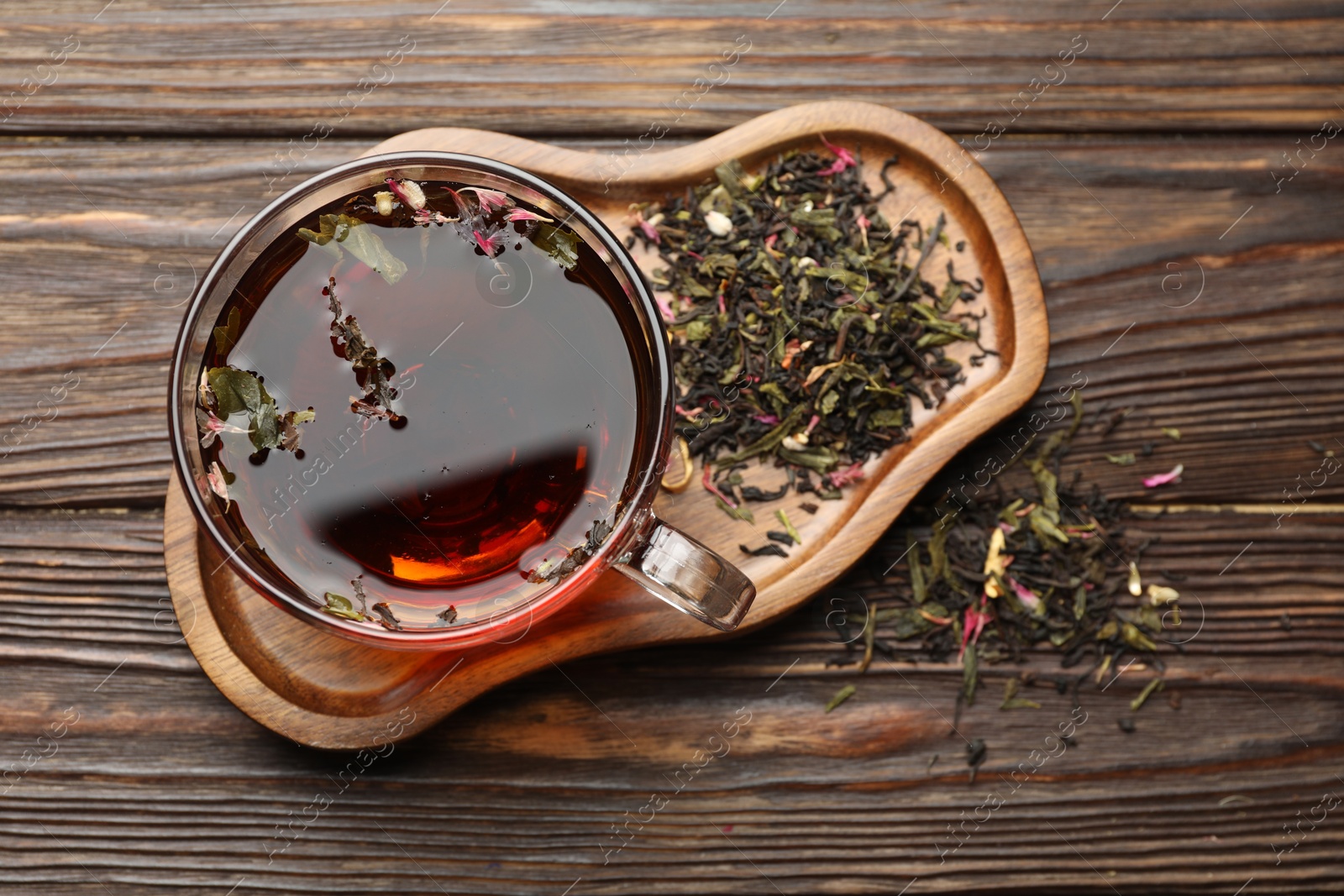 Aromatic herbal tea in glass cup and dry leaves on wooden table, flat lay Photo of Aromatic herbal tea in glass cup and dry leaves on wooden table, flat lay