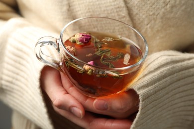 Photo of Woman with glass cup of aromatic herbal tea, closeup