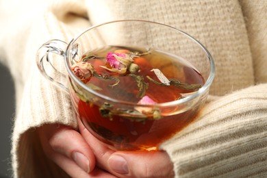 Photo of Woman with glass cup of aromatic herbal tea, closeup