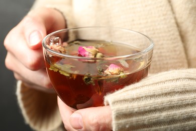 Photo of Woman with glass cup of aromatic herbal tea, closeup