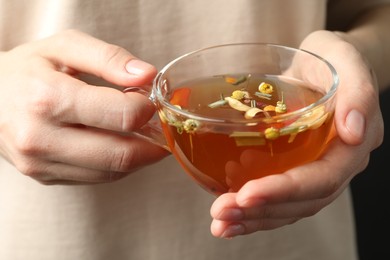 Photo of Woman with glass cup of aromatic herbal tea, closeup