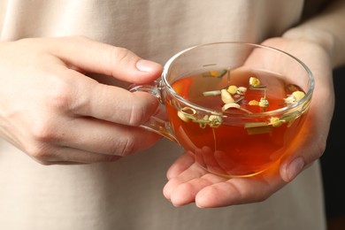 Photo of Woman with glass cup of aromatic herbal tea, closeup