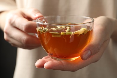Photo of Woman with glass cup of aromatic herbal tea, closeup