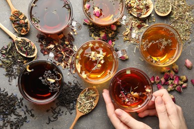 Photo of Woman with aromatic herbal tea, dry leaves and flowers at grey table, top view