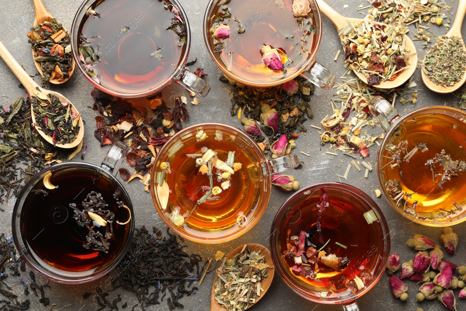 Aromatic herbal tea in glass cups, dry leaves and flowers on grey table, flat lay Photo of Aromatic herbal tea in glass cups, dry leaves and flowers on grey table, flat lay