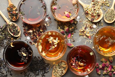 Photo of Aromatic herbal tea in glass cups, dry leaves and flowers on grey table, flat lay