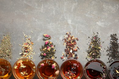 Photo of Aromatic herbal tea in glass cups, dry leaves and flowers on grey table, flat lay. Space for text