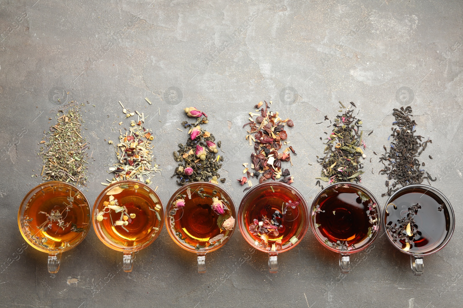 Aromatic herbal tea in glass cups, dry leaves and flowers on grey table, flat lay. Space for text Photo of Aromatic herbal tea in glass cups, dry leaves and flowers on grey table, flat lay. Space for text