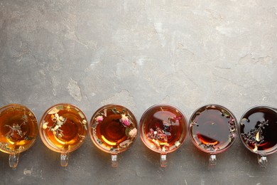 Photo of Aromatic herbal tea in glass cups on grey table, flat lay. Space for text