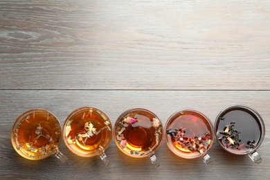 Photo of Aromatic herbal tea in glass cups on wooden table, flat lay. Space for text