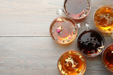 Photo of Aromatic herbal tea in glass cups on wooden table, flat lay. Space for text