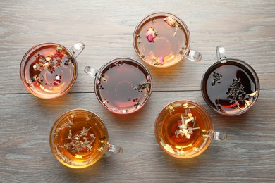 Photo of Aromatic herbal tea in glass cups on wooden table, flat lay