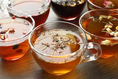 Photo of Aromatic herbal tea in glass cups on wooden table, closeup