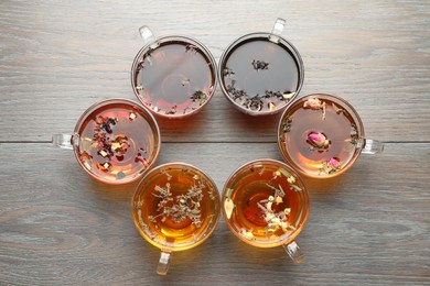 Photo of Aromatic herbal tea in glass cups on wooden table, flat lay