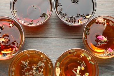 Photo of Aromatic herbal tea in glass cups on wooden table, flat lay. Space for text