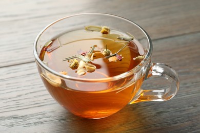 Photo of Aromatic herbal tea in glass cup on wooden table, closeup