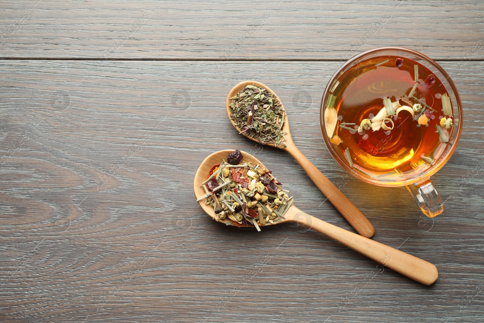 Aromatic herbal tea in glass cup and dry leaves on wooden table, flat lay. Space for text Photo of Aromatic herbal tea in glass cup and dry leaves on wooden table, flat lay. Space for text