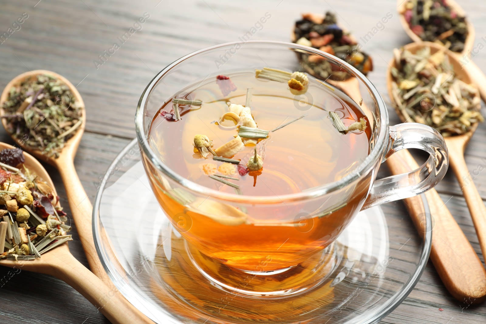 Aromatic herbal tea in glass cup and dry leaves on wooden table, closeup Photo of Aromatic herbal tea in glass cup and dry leaves on wooden table, closeup