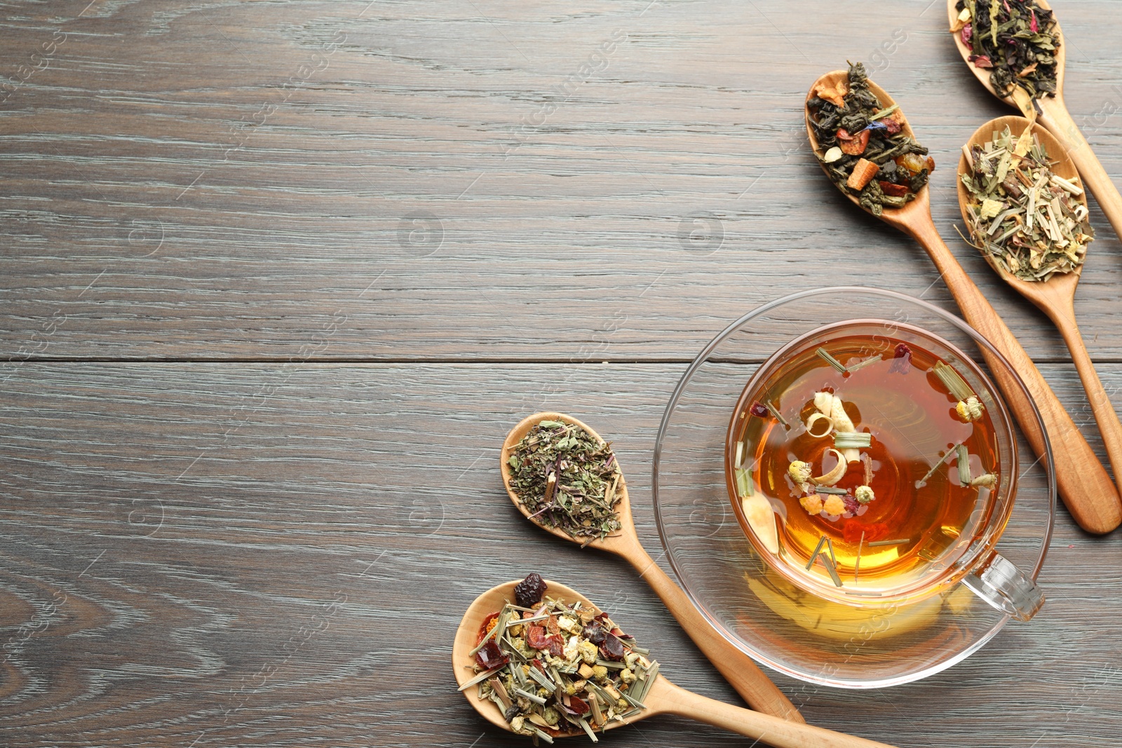 Aromatic herbal tea in glass cup and dry leaves on wooden table, flat lay. Space for text Photo of Aromatic herbal tea in glass cup and dry leaves on wooden table, flat lay. Space for text