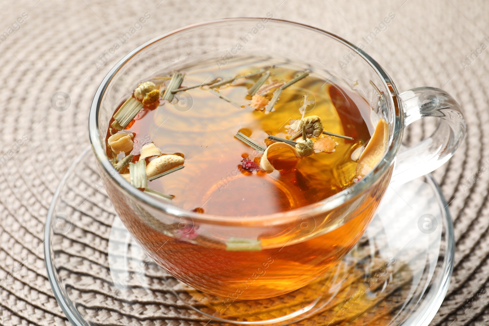 Aromatic herbal tea in glass cup on mat, closeup Photo of Aromatic herbal tea in glass cup on mat, closeup