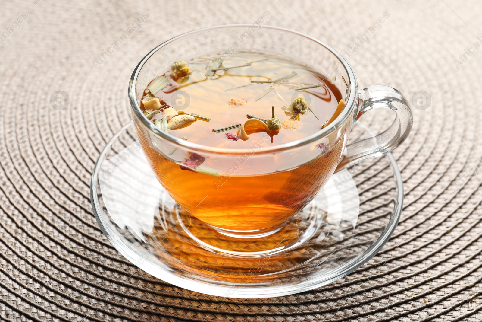 Aromatic herbal tea in glass cup on mat, closeup Photo of Aromatic herbal tea in glass cup on mat, closeup