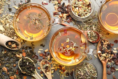 Photo of Aromatic herbal tea and dry leaves on grey table, flat lay