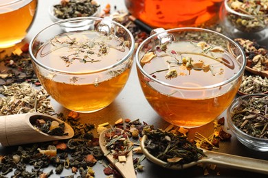 Photo of Aromatic herbal tea and dry leaves on grey table, closeup