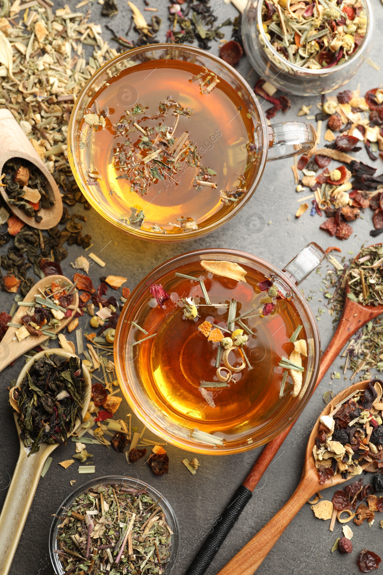 Aromatic herbal tea and dry leaves on grey table, flat lay Photo of Aromatic herbal tea and dry leaves on grey table, flat lay
