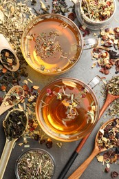 Photo of Aromatic herbal tea and dry leaves on grey table, flat lay