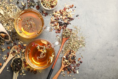 Photo of Aromatic herbal tea and dry leaves on grey table, flat lay. Space for text