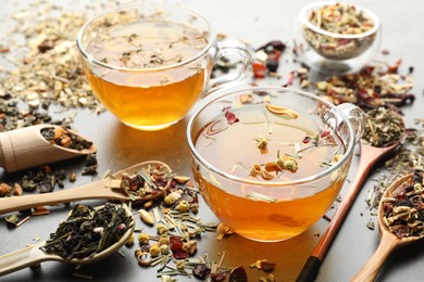 Photo of Aromatic herbal tea and dry leaves on grey table, closeup