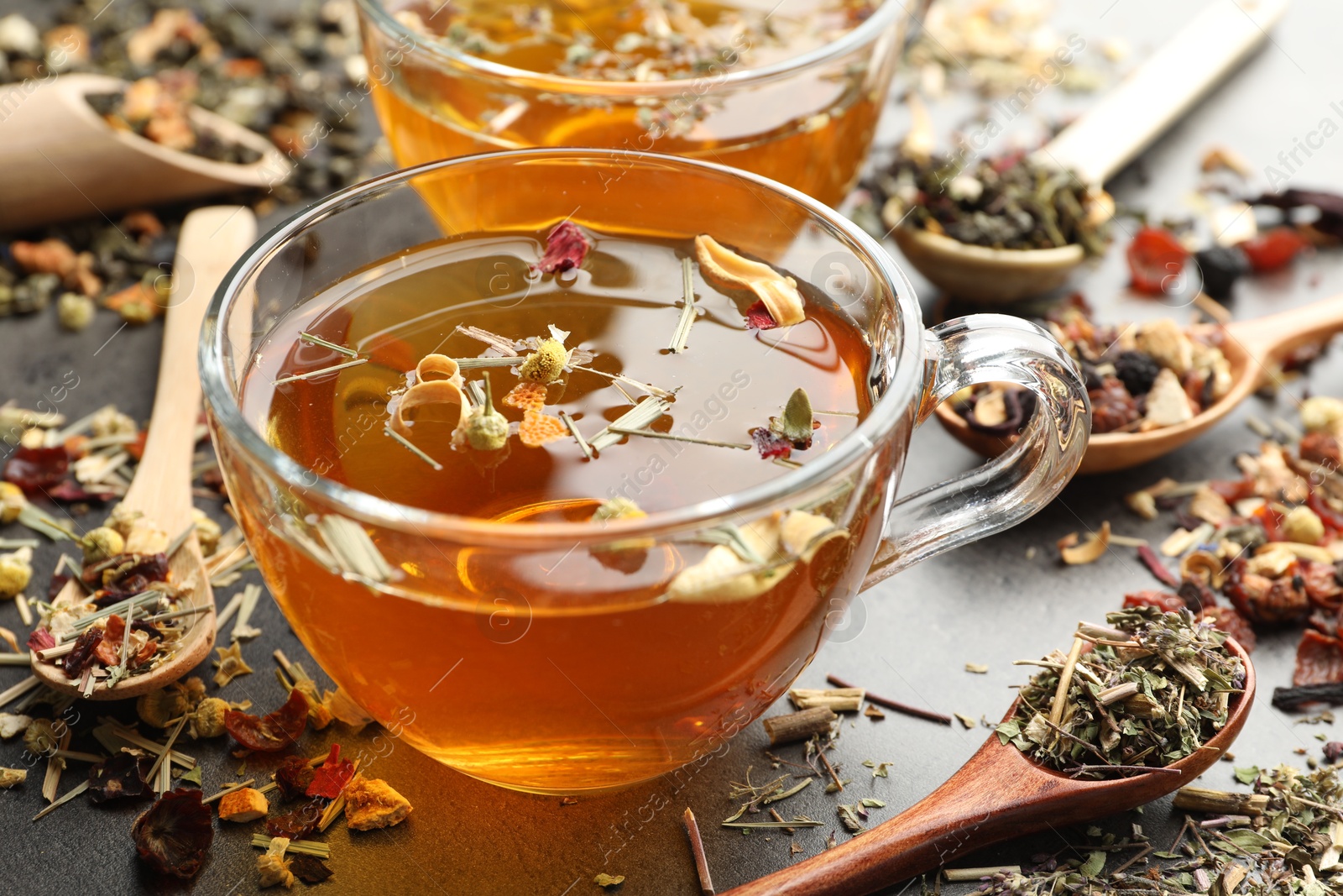 Aromatic herbal tea and dry leaves on grey table, closeup Photo of Aromatic herbal tea and dry leaves on grey table, closeup