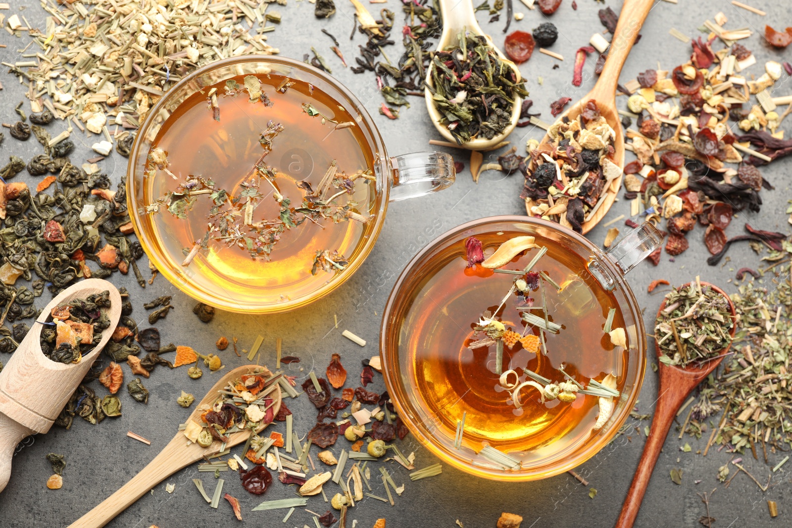 Aromatic herbal tea and dry leaves on grey table, flat lay Photo of Aromatic herbal tea and dry leaves on grey table, flat lay