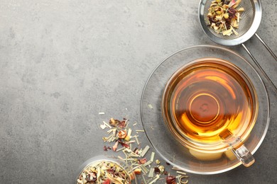 Photo of Aromatic herbal tea and dry leaves on grey table, flat lay. Space for text