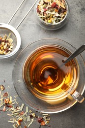 Photo of Aromatic herbal tea and dry leaves on grey table, flat lay