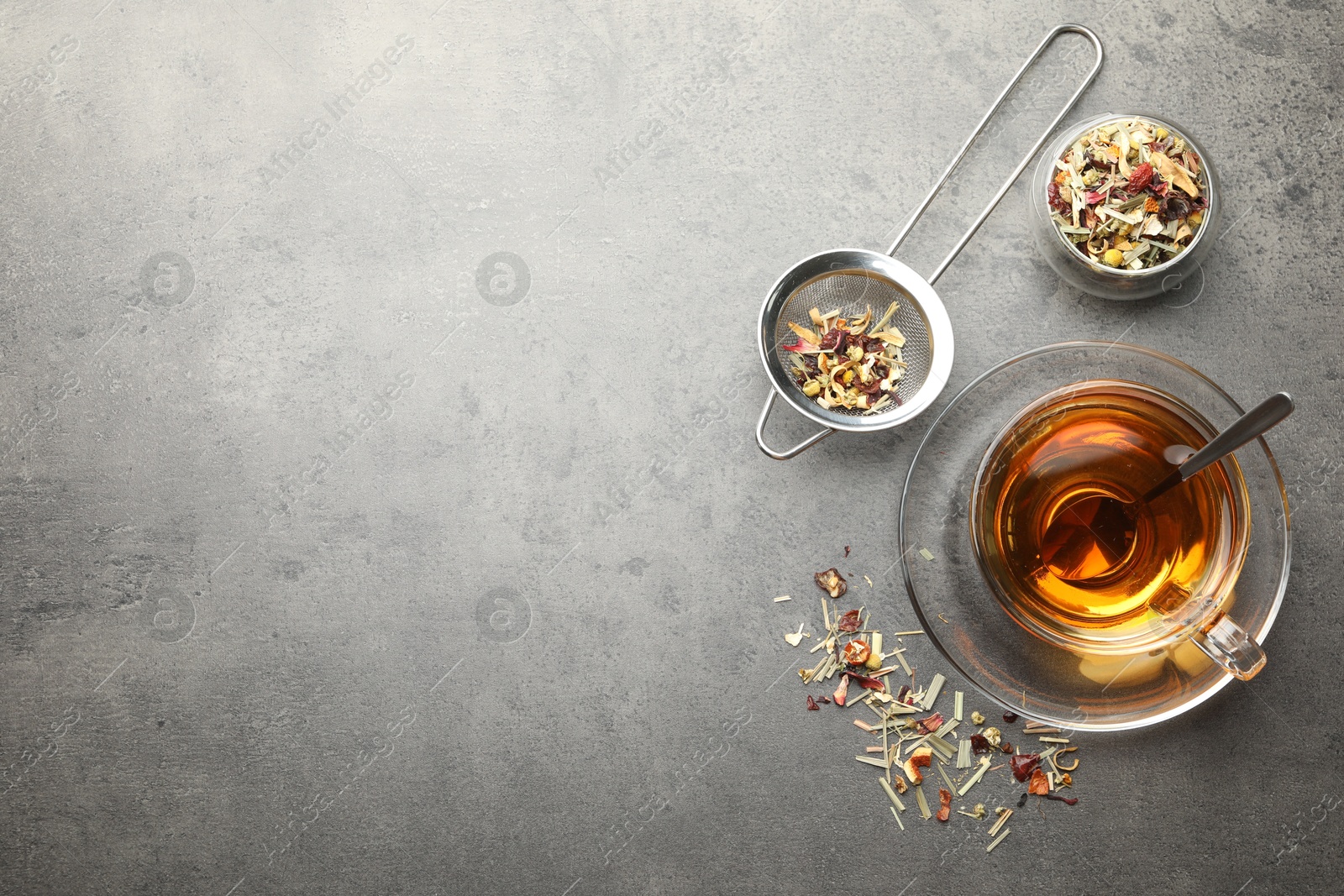 Aromatic herbal tea and dry leaves on grey table, flat lay. Space for text Photo of Aromatic herbal tea and dry leaves on grey table, flat lay. Space for text