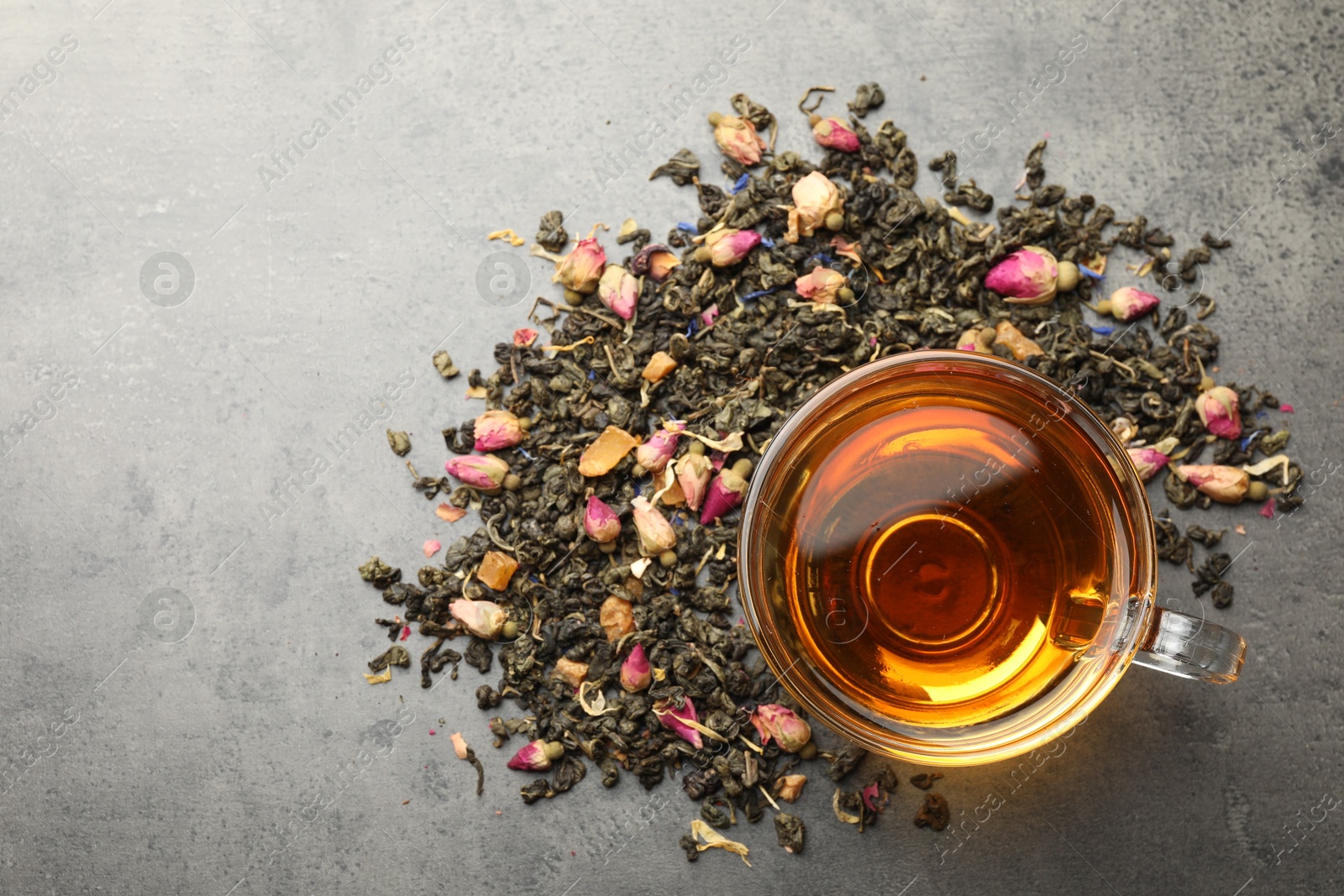 Aromatic herbal tea, dry leaves and flowers on grey table, flat lay. Space for text Photo of Aromatic herbal tea, dry leaves and flowers on grey table, flat lay. Space for text