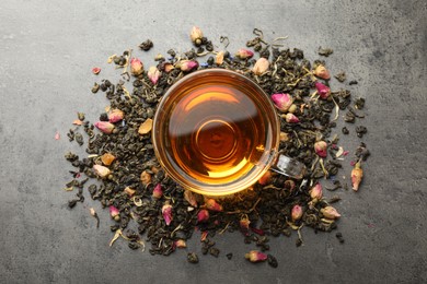 Photo of Aromatic herbal tea, dry leaves and flowers on grey table, flat lay