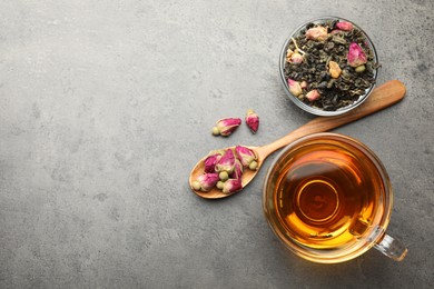 Photo of Aromatic herbal tea, dry leaves and flowers on grey table, flat lay. Space for text