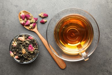 Photo of Aromatic herbal tea, dry leaves and flowers on grey table, flat lay