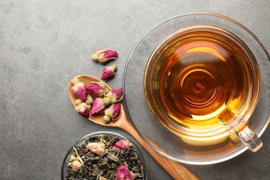 Photo of Aromatic herbal tea, dry leaves and flowers on grey table, flat lay. Space for text