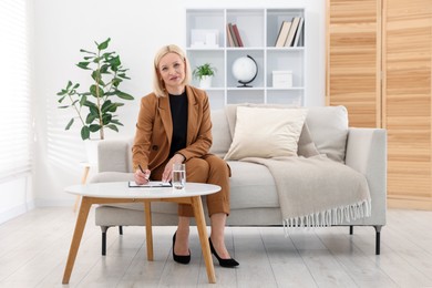 Photo of Professional psychologist taking notes at table in office