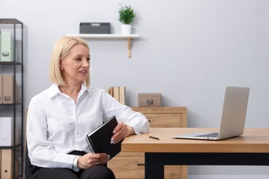 Photo of Professional psychologist with notebook at table in office