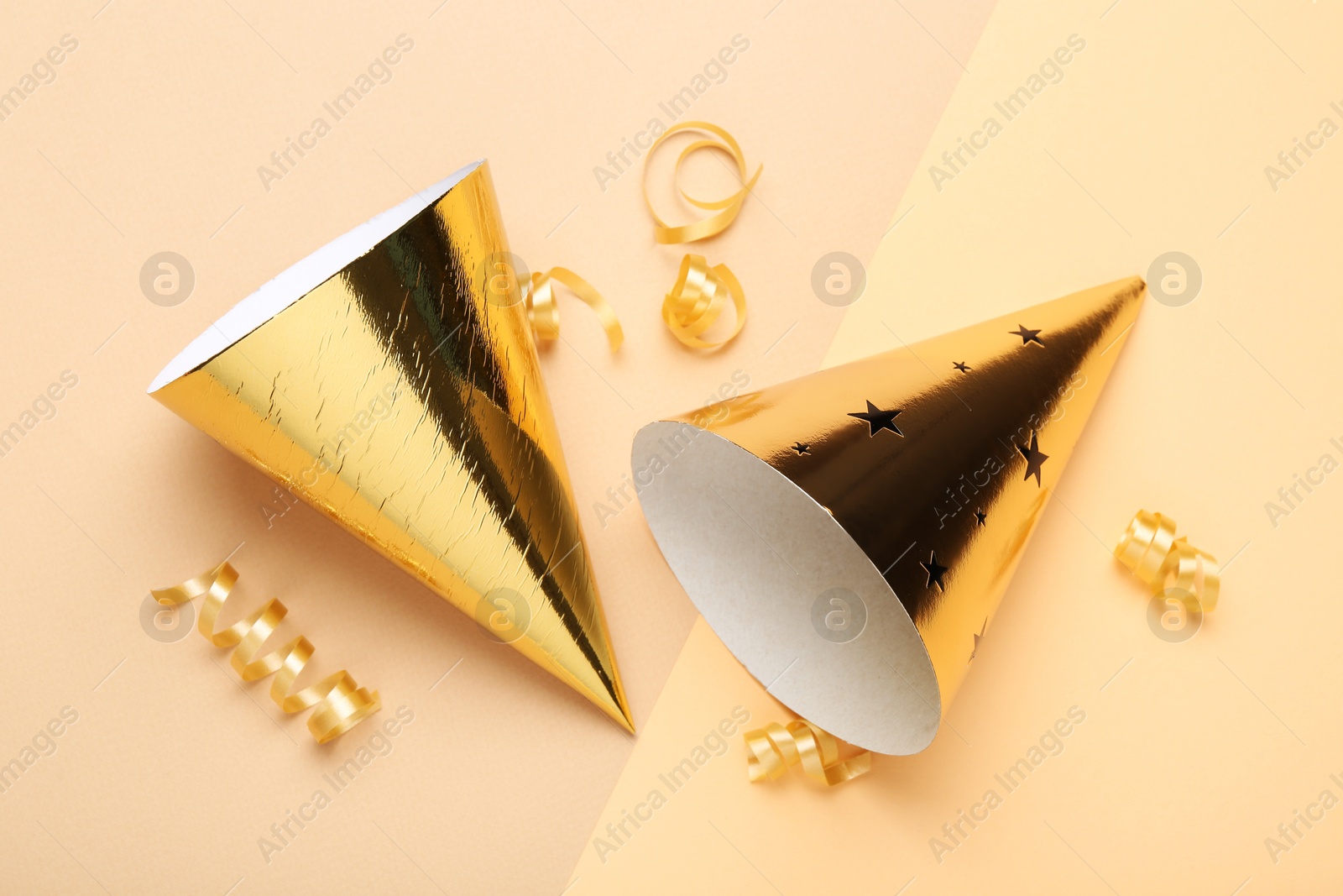 Party hats and streamers on color background, flat lay Photo of Party hats and streamers on color background, flat lay