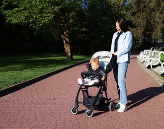 Photo of Mother walking with her baby in stroller at park
