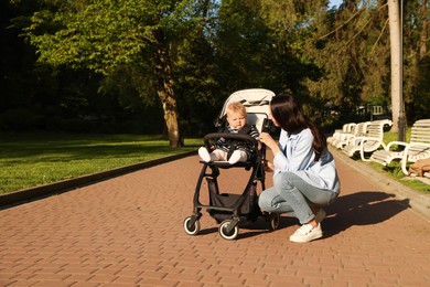 Photo of Mother with her cute baby in stroller at park. Space for text