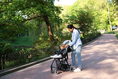 Photo of Mother walking with her baby in stroller at park. Space for text